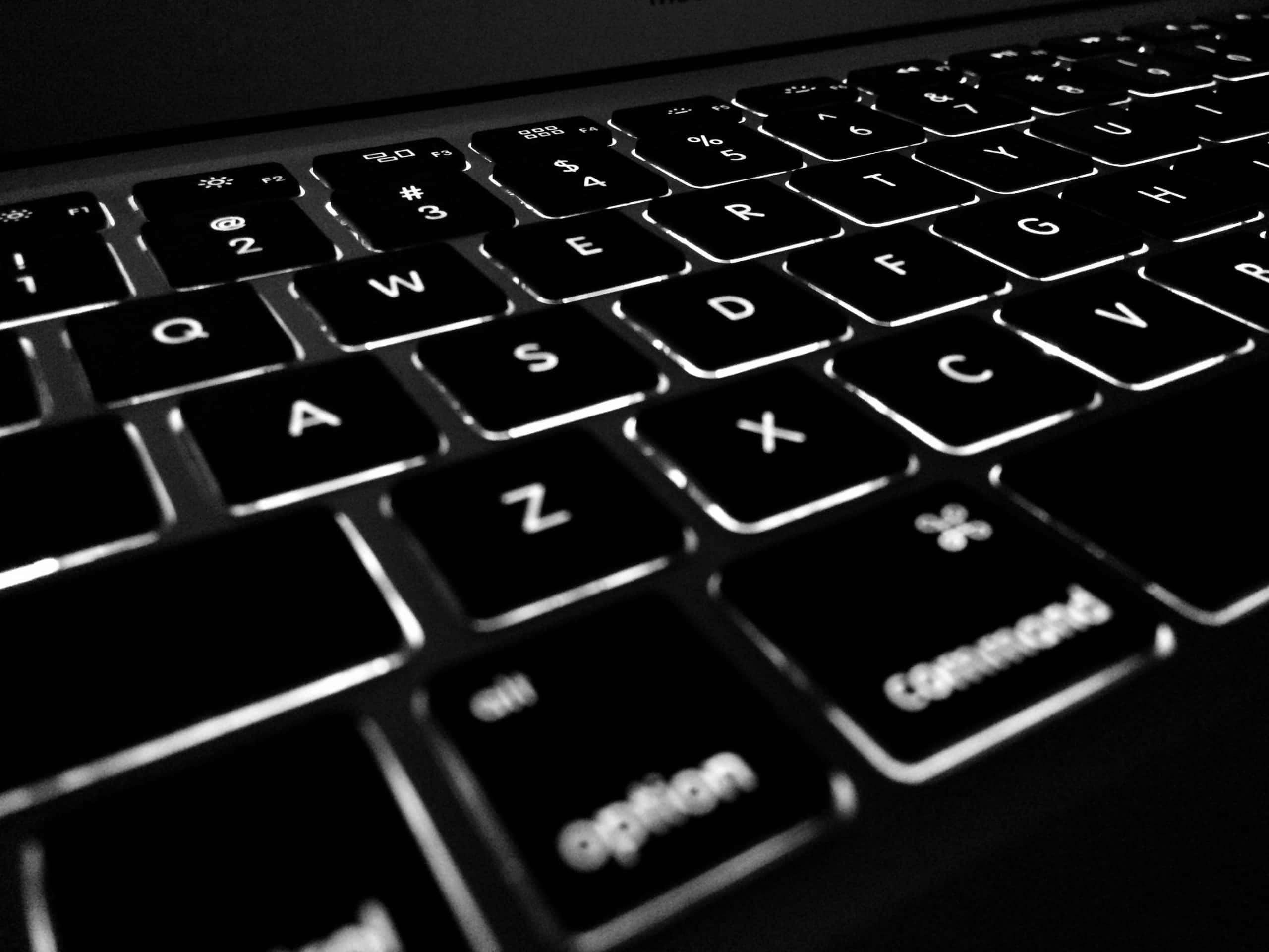 Detail of a black, white illuminated laptop keyboard
